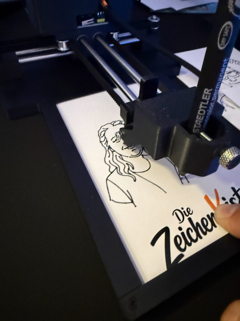 Zeichenroboter zeichnet eine Karikatur auf eine ZeichenKiste-Karte